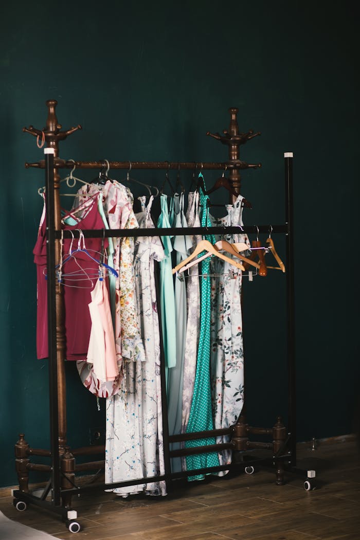A stylish collection of dresses on a wooden clothes rack against a dark wall, creating a chic aesthetic.